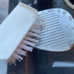 Golf Club being cleaned with a soft bristle brush