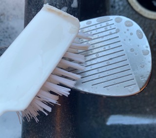 Golf Club being cleaned with a soft bristle brush