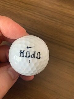 Front of mojo golf ball from a cheap recycled batch of golf balls.