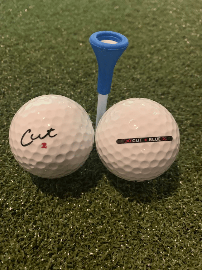 Cut golf balls review, two cut golf balls with a golf tee.