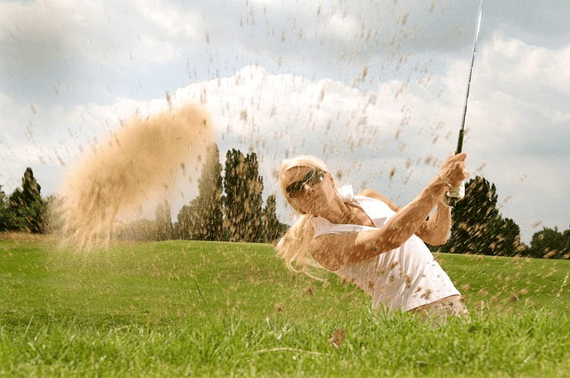 Woman golfer hitting out of the sand