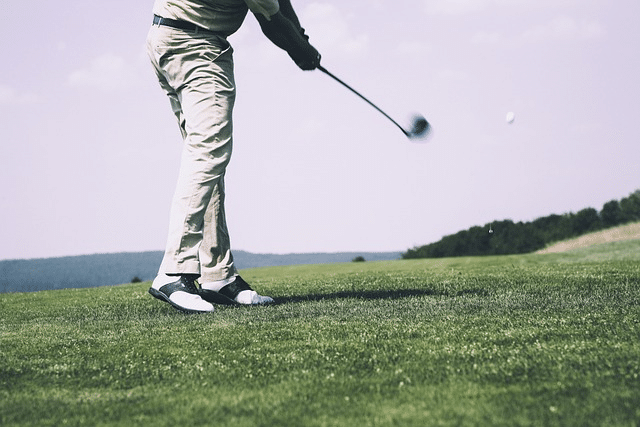 A golfer selecting a golf club from a golf bag