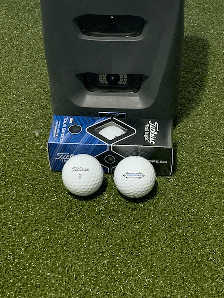 Titleist Tour Speed Golf Balls in front of a launch monitor on a hitting mat.