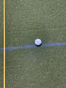 Golf ball with an alignment rod and a chalk line slightly behind the ball