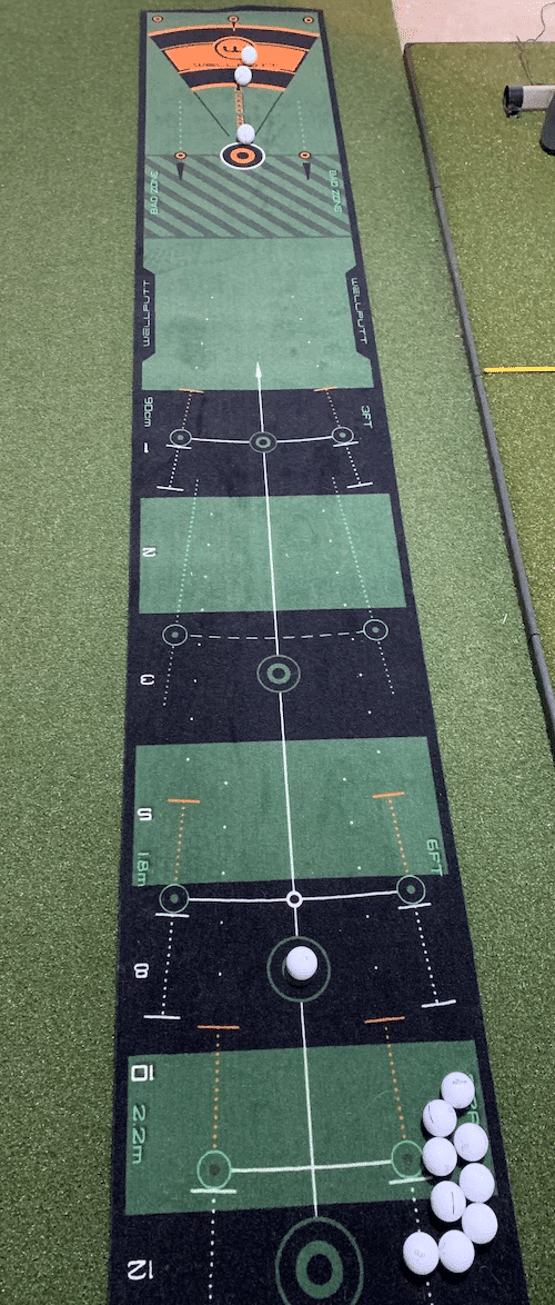 Wellputt putting mat with with golf balls placed on green carpet.